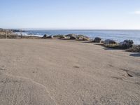 a parking lot overlooking the ocean with three large rocks in the background and two smaller rocks at the far end of the road