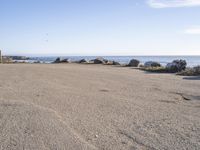 a parking lot overlooking the ocean with three large rocks in the background and two smaller rocks at the far end of the road