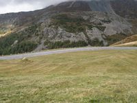 a car parked on a country road next to a tall mountain side with a low cloud above the top of it