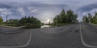 this is a fish eye lens showing a country road with a river running down it