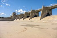 the dam wall with concrete walls and railings is covered in water with a blue sky