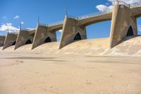 the dam wall with concrete walls and railings is covered in water with a blue sky