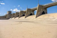 the dam wall with concrete walls and railings is covered in water with a blue sky