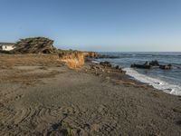 a grassy field by the shore and a cliff with rocks in the ocean in the background