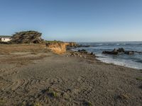 a grassy field by the shore and a cliff with rocks in the ocean in the background