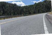 the asphalt road has some white marking on it and some trees, and a hill with hills