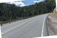 the asphalt road has some white marking on it and some trees, and a hill with hills