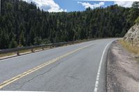 the asphalt road has some white marking on it and some trees, and a hill with hills