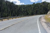 the asphalt road has some white marking on it and some trees, and a hill with hills