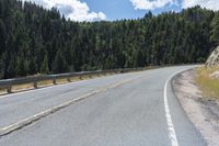 the asphalt road has some white marking on it and some trees, and a hill with hills