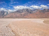 there is a large expanse of rocks in the middle of a desert field with mountains