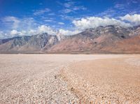 there is a large expanse of rocks in the middle of a desert field with mountains