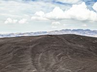 the desert is covered in thinly eroded layers and sand covered mountains and the clouds are still there