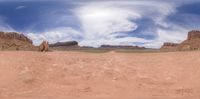 a scenic and empty area that is all dirt and sand with mountains and clouds in the background