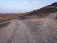 a truck on a dirt road in the desert with rocks and stones on the ground