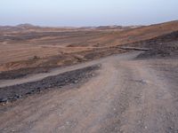 a truck on a dirt road in the desert with rocks and stones on the ground