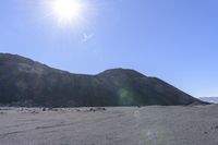 a dirt road in a mountain with hills in the back ground and sunlight shining behind it