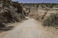 the dirt road leads to the hills and a steep cliff area in the background is covered with rocks