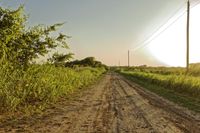a dirt road is shown in the middle of nowhere with the sun rising over the horizon
