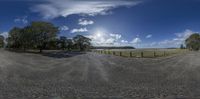 a wide angle shot of a dirt road in the sun with the sky behind it