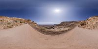 the view of a dirt road and a large rock outcropping in the desert