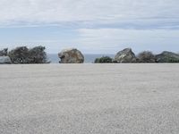 an empty parking lot near the ocean in california with one single plane flying overhead over the resturance