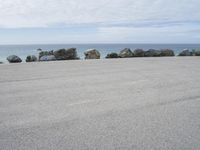 an empty parking lot near the ocean in california with one single plane flying overhead over the resturance