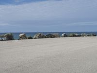 an empty parking lot near the ocean in california with one single plane flying overhead over the resturance