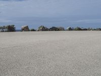 an empty parking lot near the ocean in california with one single plane flying overhead over the resturance