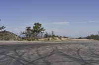 a view along a dirt road of an empty field and mountains in the distance of the scene