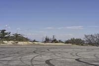 a view along a dirt road of an empty field and mountains in the distance of the scene