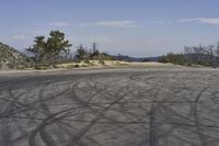 a view along a dirt road of an empty field and mountains in the distance of the scene