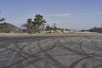 a view along a dirt road of an empty field and mountains in the distance of the scene