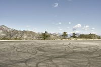 a view along a dirt road of an empty field and mountains in the distance of the scene