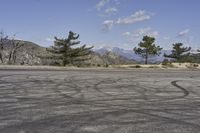 a view along a dirt road of an empty field and mountains in the distance of the scene