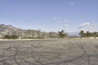 a view along a dirt road of an empty field and mountains in the distance of the scene