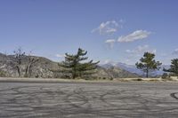 a view along a dirt road of an empty field and mountains in the distance of the scene