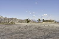 a view along a dirt road of an empty field and mountains in the distance of the scene