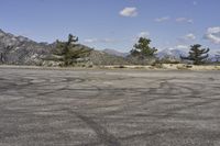 a view along a dirt road of an empty field and mountains in the distance of the scene