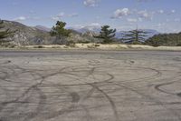 a view along a dirt road of an empty field and mountains in the distance of the scene