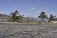 a view along a dirt road of an empty field and mountains in the distance of the scene