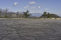 a view along a dirt road of an empty field and mountains in the distance of the scene