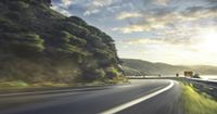 a vehicle drives down an empty, windy highway to the mountains on a sunny day