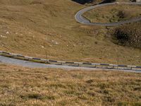 a car is driving down the winding road in a hilly valley with some rocks in the background