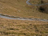 a car is driving down the winding road in a hilly valley with some rocks in the background