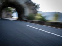 an blurred image of a car driving along a road with lots of green shrubs on the side