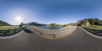 an 360 - fish eye view of the road with mountains in the background and a large lake