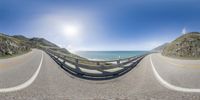 360 - zoom photograph of scenic view on curved road by the ocean near cliffs with cloudy sky and sun