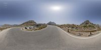 a circular panoramic view of a road and the mountains in the background that appears to be curved