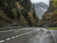 a car is driving down an empty highway during the rain and foggy morning, with mountain in the background